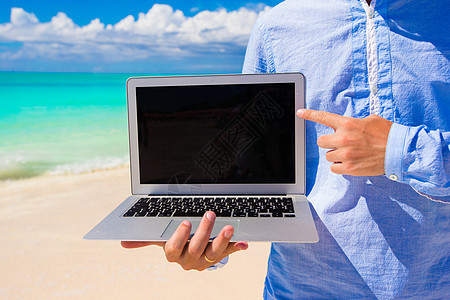 海滩度假期间带笔记本电脑的年轻人旅行支撑记事本互联网热带海岸假期游客商务海洋图片