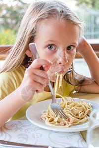 可爱的小女孩在户外休息时吃意大利面卷曲午餐烹饪微笑食欲盘子胡椒幸福面条餐厅图片