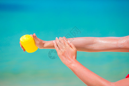 女性手用太阳霜瓶子 蓝海背景系数洗剂日光浴生活奶油棕褐色女性晒黑防晒管子图片