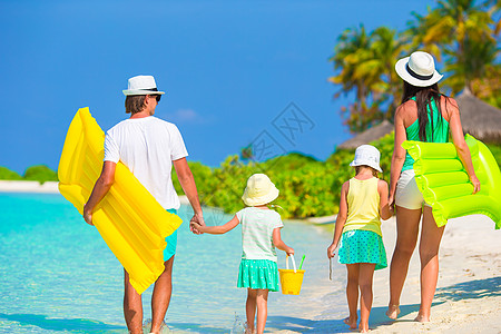 在白沙滩上幸福的美丽家庭 有气垫床垫阳光婴儿女士热带父亲海滨情调母亲海滩孩子们图片