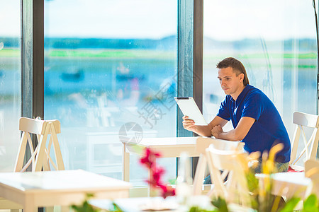 在机场咖啡厅用笔记本电脑工作的年轻人等待登机酒吧木板旅行药片游客男人旅游航班航空公司生意人图片