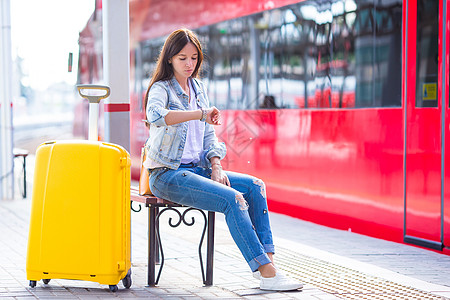 在火车平台上携带行李的年轻女子等待气压表达式木板飞机铁路车站女性运输游客列车旅游车皮背景图片
