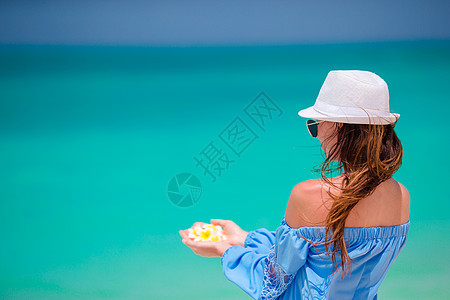 美丽的frangipani鲜花在女性手中 背景背景 在白色海滩的绿绿海女孩波纹海洋温泉娱乐卫生气候鸡蛋花天堂保健图片