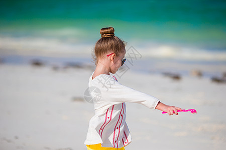 暑假期间海滩上可爱的小女孩在沙滩上异国海岸太阳镜热带微笑海滨闲暇喜悦太阳海岸线图片