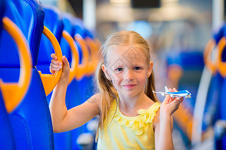 可爱的小女孩乘火车旅行 与飞机型号一起玩乐在手游客微笑运输运动车站座位女儿公共汽车速度闲暇图片