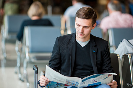 青年男子在机场等待登机时看报纸 身穿西装的零星年轻商务人士 ( 纽约邮报 )图片