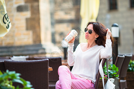 欧洲城市快乐的年轻女子喝咖啡 高加索旅游者在空城享受欧洲度假 Europepean成人背包指导帽子女士学生旅行街道游客可可图片