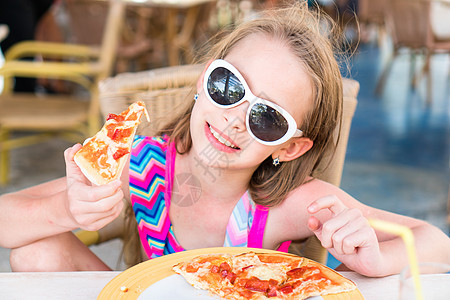 坐在晚餐桌边吃披萨的可爱小女孩的肖像假期营养小吃面团食物餐厅午餐早餐女孩女儿图片