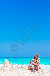 小女孩在热带度假期间玩沙滩玩具的热带假期海岸喜悦海洋情调海岸线女孩游泳衣享受童年幸福图片