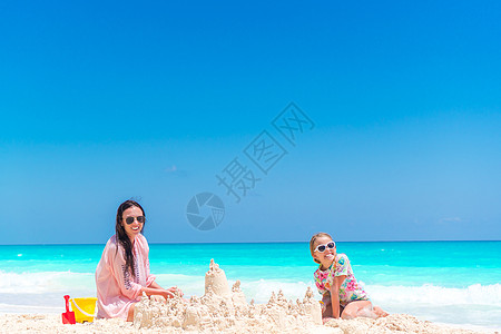 家庭在热带白色海滩制作沙堡 妈妈和两个女孩在热带海滩上玩沙天堂假期游泳衣喜悦海岸父母童年母亲海洋闲暇图片
