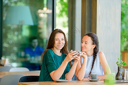 快乐笑容的年轻女子在咖啡馆喝咖啡 交流和友谊概念假期桌子顾客饮料闲暇街道八卦咖啡店女朋友城市图片