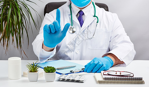 穿白大衣和蓝色乳胶手套的男男性医生坐在Whit手指男人实验室职场病人药品桌子咨询医师办公室图片