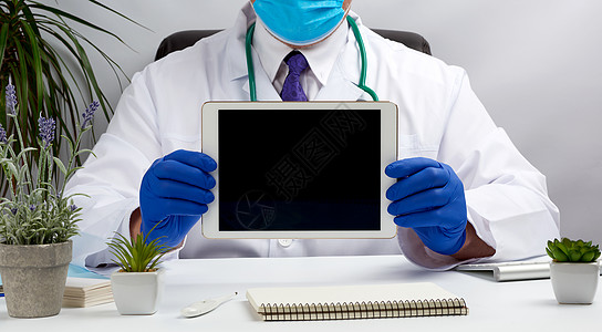 男医生坐在白外衣和紧抱的桌子上图片