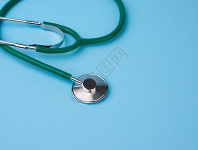 蓝色背景的绿色金属医学听诊器;图片