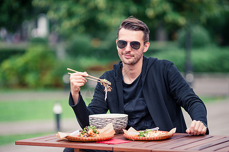 吃饭的年轻人在街上抢走面条筷子男人街道午餐菜单旅游旅行生活潮人游客图片