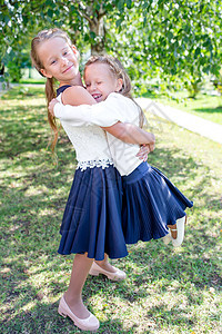 两个可爱的小女孩 在学校门口摆着姿势 装模作样娱乐考试教育双胞胎学习姐妹朋友幸福小学生童年图片