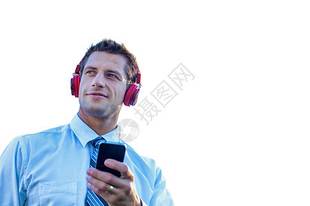 剪断笑笑的成熟商务人士 在他智能手机上监听音乐 用耳机图片