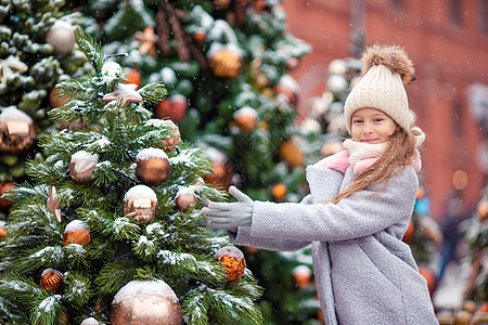 新的一年 在雪地的fir tree树枝附近的小快乐女孩幸福女孩帽子传统礼物手套城市雪花森林童年图片