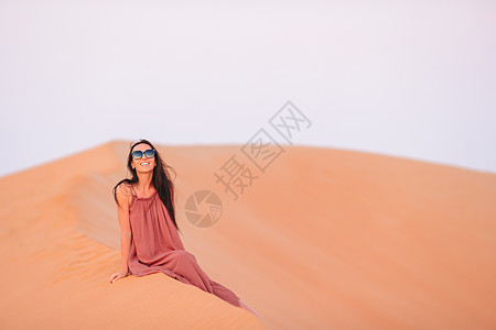 在阿拉伯联合酋长国沙漠中的沙丘中女童居于沙丘中日落滚动干旱风景阳光女士女孩假期天空栖息地图片
