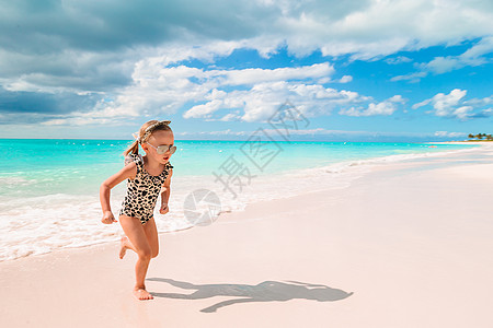 度假期间海滩上可爱的小女孩在caribbean度假海岸线游客热带闲暇情调支撑快乐沿海旅行裙子图片