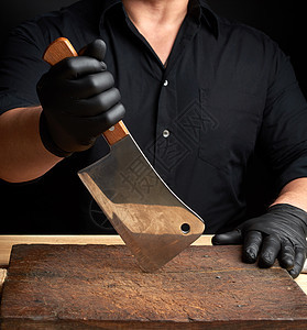 穿黑色衬衫和黑乳胶手套的厨师拿着大便服屠夫锐化木头工作室厨房工作工具金属男性成人图片