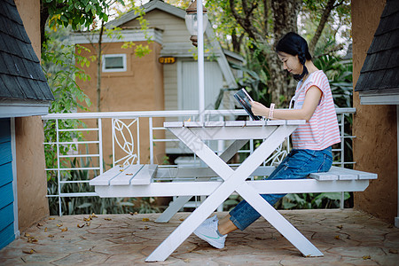 在阳台读书的年轻亚洲女孩微笑爱好休息智慧成人教育小说公园时间文学图片