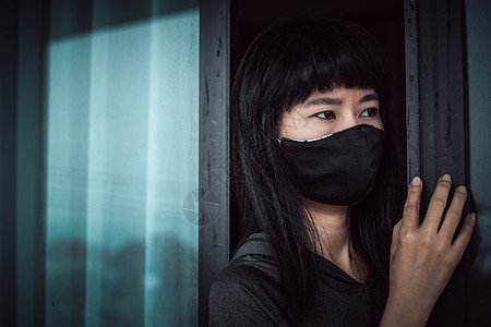亚洲妇女为自我隔离和社会不和谐而住在家里的亚洲妇女危机预防房子流感危险面具情感停留寂寞窗户图片