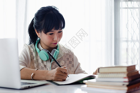 在纸上写字 使用笔记本电脑和在家工作的亚洲妇女图片