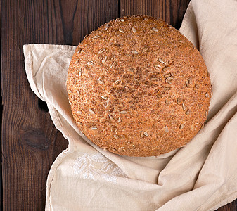 烤圆黑麦面包 在米蜂纺织上加向日葵籽木板饮食面包面粉粮食桌子乡村毛巾谷物餐巾图片