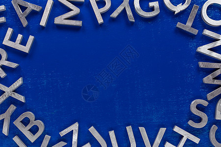 蓝色背景上由银金属英文字母字符制成的框架模型图片