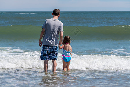 面对海浪的父亲和年轻女儿的近视面图片
