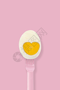 粉红色背景最小风格的粉红色叉子上的半熟鸡蛋图片