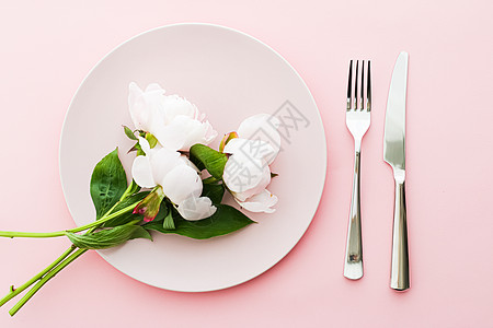 餐盘和餐具 配有小鲜花作为婚礼装饰品 放在粉红背景 活动装饰最顶桌板以及菜单品牌桌子新娘生日晚餐推广花朵花束环境礼物广告图片
