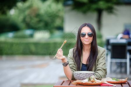 吃东西的年轻女人 在街上把面条抢走午餐菜单顾客女士旅行服务筷子潮人店铺社论图片