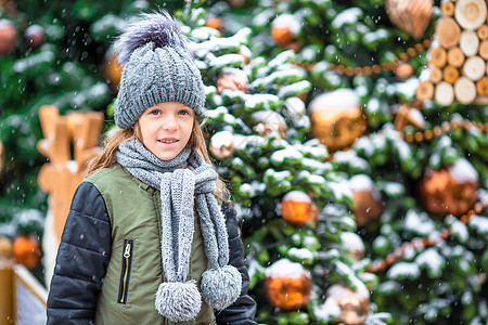 新的一年 在雪地的fir tree树枝附近的小快乐女孩街道手套季节森林城市童年枞树微笑地标市场图片