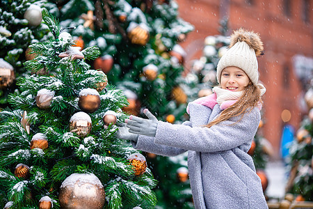 圣诞动图新的一年 在雪地的fir tree树枝附近的小快乐女孩女孩枞树幸福帽子孩子季节传统童年喜悦森林背景