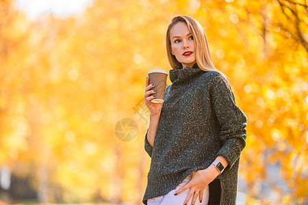 秋瀑概念  美丽的女人在秋公园喝咖啡 在秋天的树叶下女孩木头森林拿铁女性饮料金发女郎叶子公园外套图片