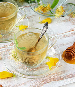 白色木板上放着菩提树茶的透明杯子食物饮料芳香药品玻璃早餐植物蜂蜜叶子草本植物图片