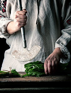 穿灰色内衣的女人正在切割新鲜索尔的绿叶植物女性食物草本植物亚麻沙拉菠菜木头桌子木板图片
