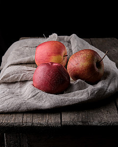 三个新鲜红苹果放在灰色纸巾上图片
