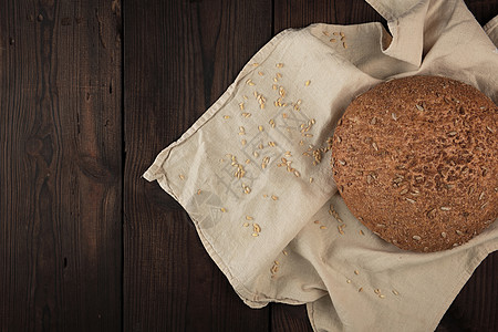 烤圆黑麦面包 在米蜂纺织上加向日葵籽棕色小麦营养毛巾面包面粉食物圆圈褐色木板图片