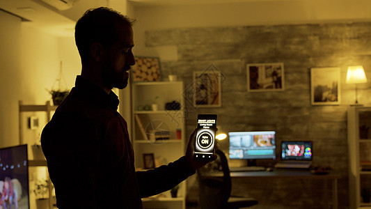 男人用智能灯光程序打开家里的灯泡 然后把灯泡打开嗓音语音电话房子技术创新电子网络手机工具图片