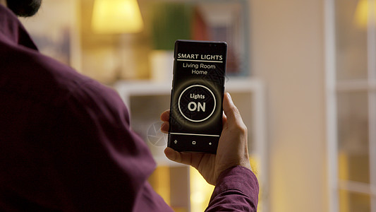近身手握着一个声音激活智能灯光应用程序 用于对房子的灯光进行调音图片