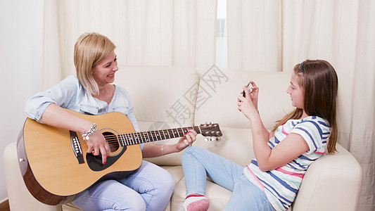 少女在拍摄她母亲用音响吉他弹奏时的照片图片