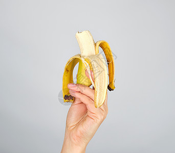白色背景的雌性手切开新鲜香蕉皮背景图片