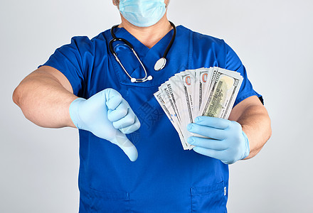 穿蓝色制服和乳胶手套的医生 一只手留着很多工资商业薪水手术贿赂金融疾病男性受贿药品图片