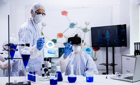 在现代实验室中使用虚拟现实模拟的化学科学家图片