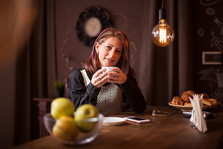 紧贴着成年女商务人士的肖像 她一边拿着咖啡边笑着微笑电话消息服装娱乐活动庆典中年潮人桌子酒吧图片