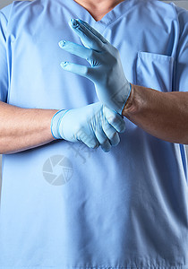 穿蓝制服的医生戴上无菌乳胶手套实验室手术外科卫生手指医疗药品安全推杆手臂图片