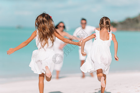 四口四口的年轻家庭度假玩得开心跑步假期爸爸海岸线海洋女孩海滩成人女士阳光图片
